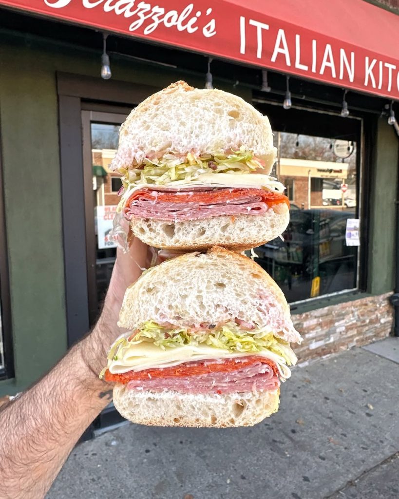 An italian sub from New Jersey being held in front of the store